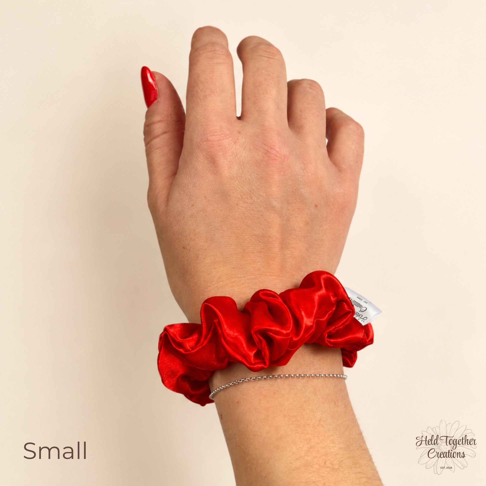 Small red satin scrunchie worn on wrist with smooth satin finish