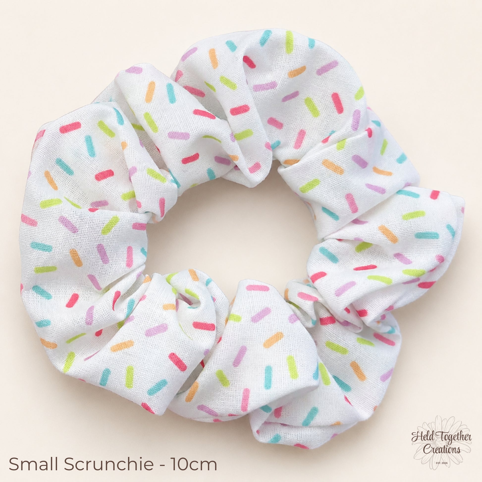 Small Rainbow Sprinkle Scrunchie on warm ivory background showing colourful sprinkle print