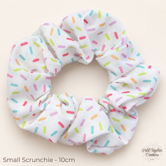 Small Rainbow Sprinkle Scrunchie on warm ivory background showing colourful sprinkle print