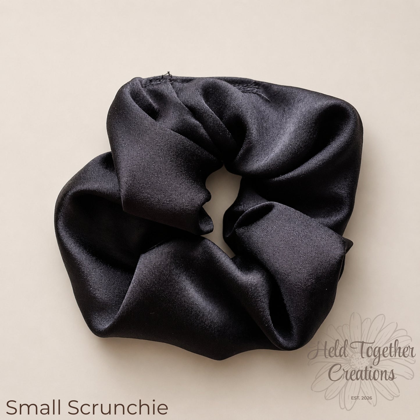 Midnight Gloss black satin scrunchies in large and small sizes styled on a soft neutral background.