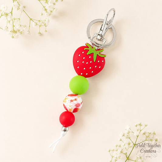 Handmade strawberry silicone bead keyring with red, green and floral beads on silver keyring hardware.