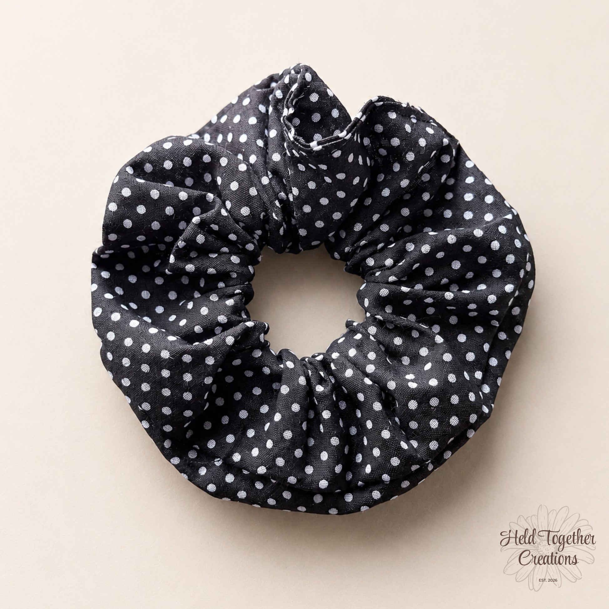 Black scrunchie with white polka dots on a beige background