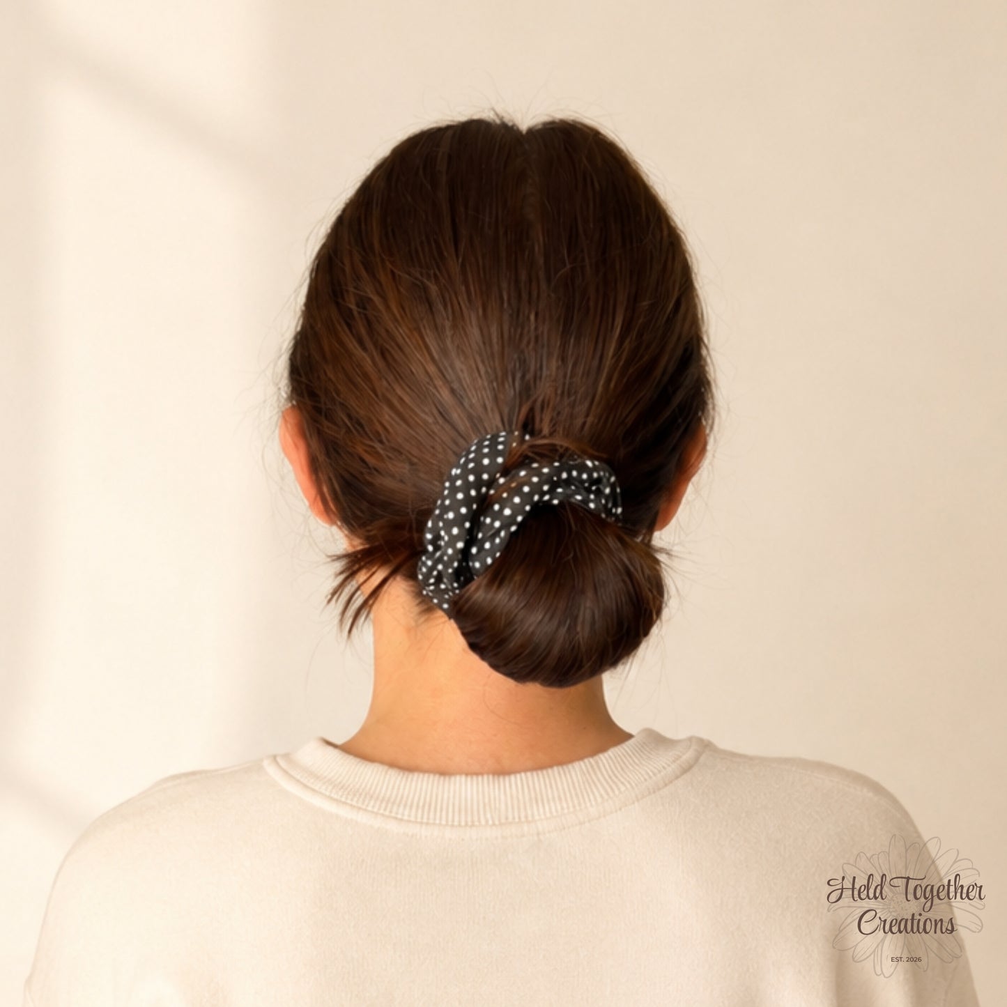 Person with a polka dot scrunchie in their hair against a plain background