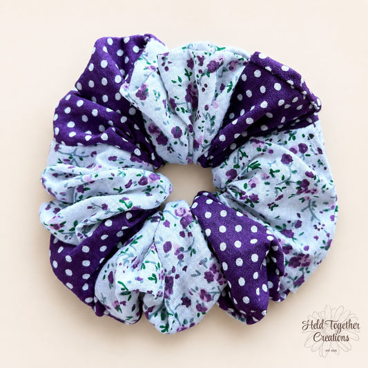 Violet Garden Scrunchie with purple polka dot and floral fabric on a warm neutral background.