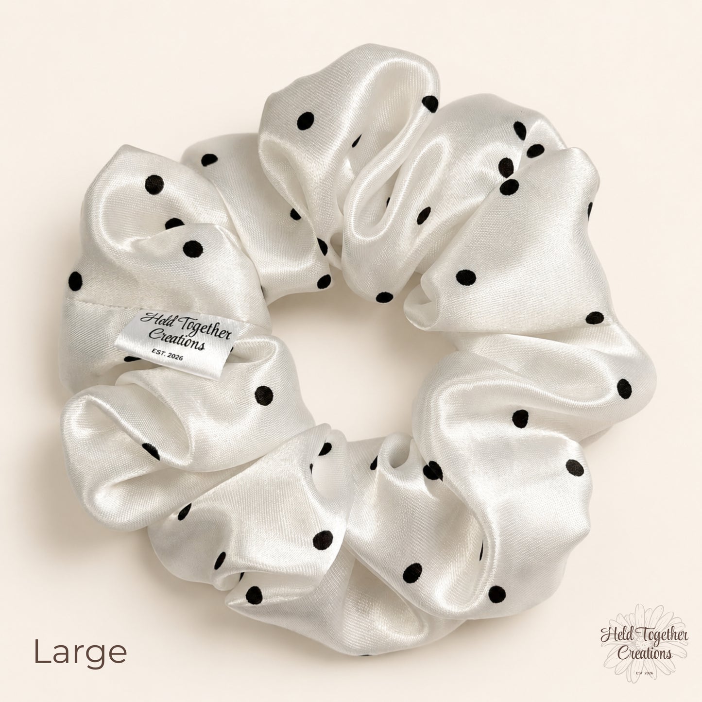 Large white satin scrunchie with black polka dots on neutral background.