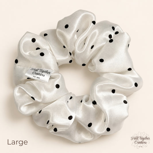 Large white satin scrunchie with black polka dots on neutral background.