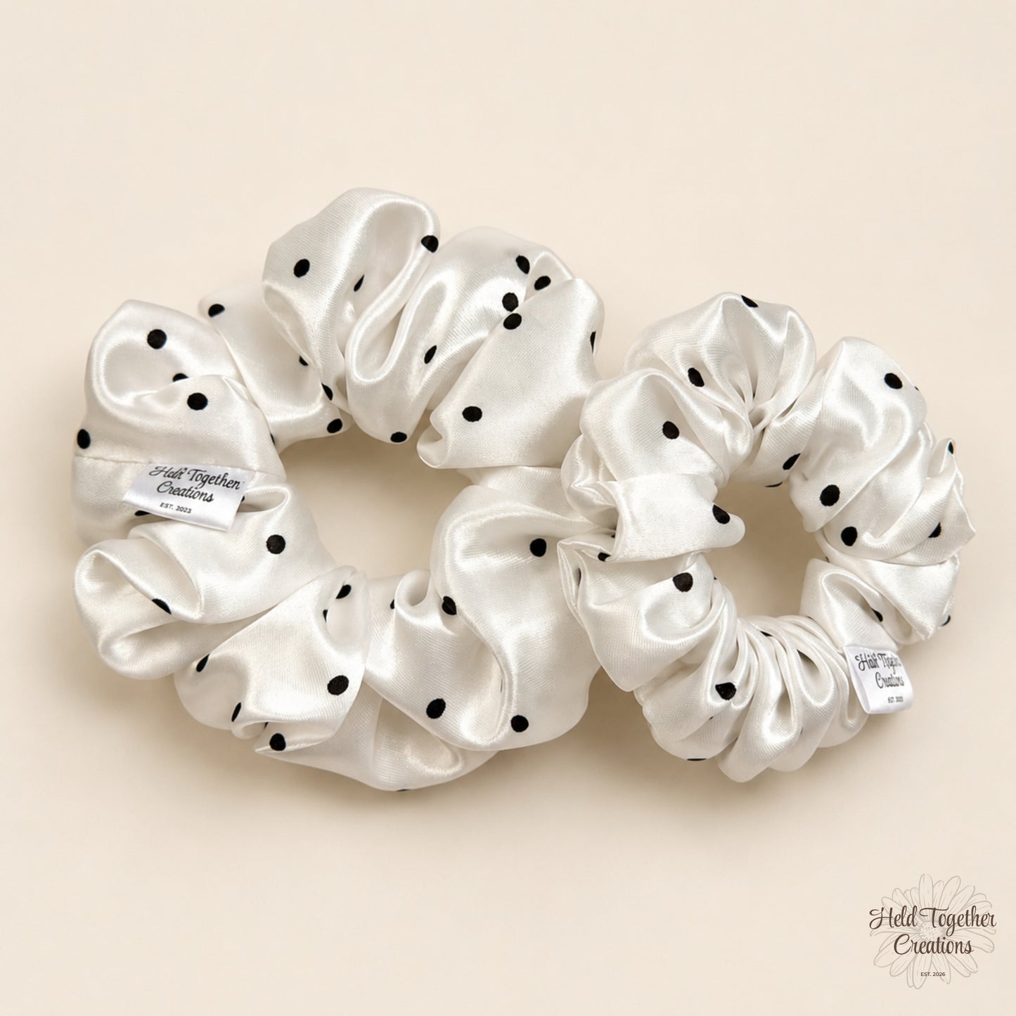 Small and large white satin scrunchies with black polka dots side by side.