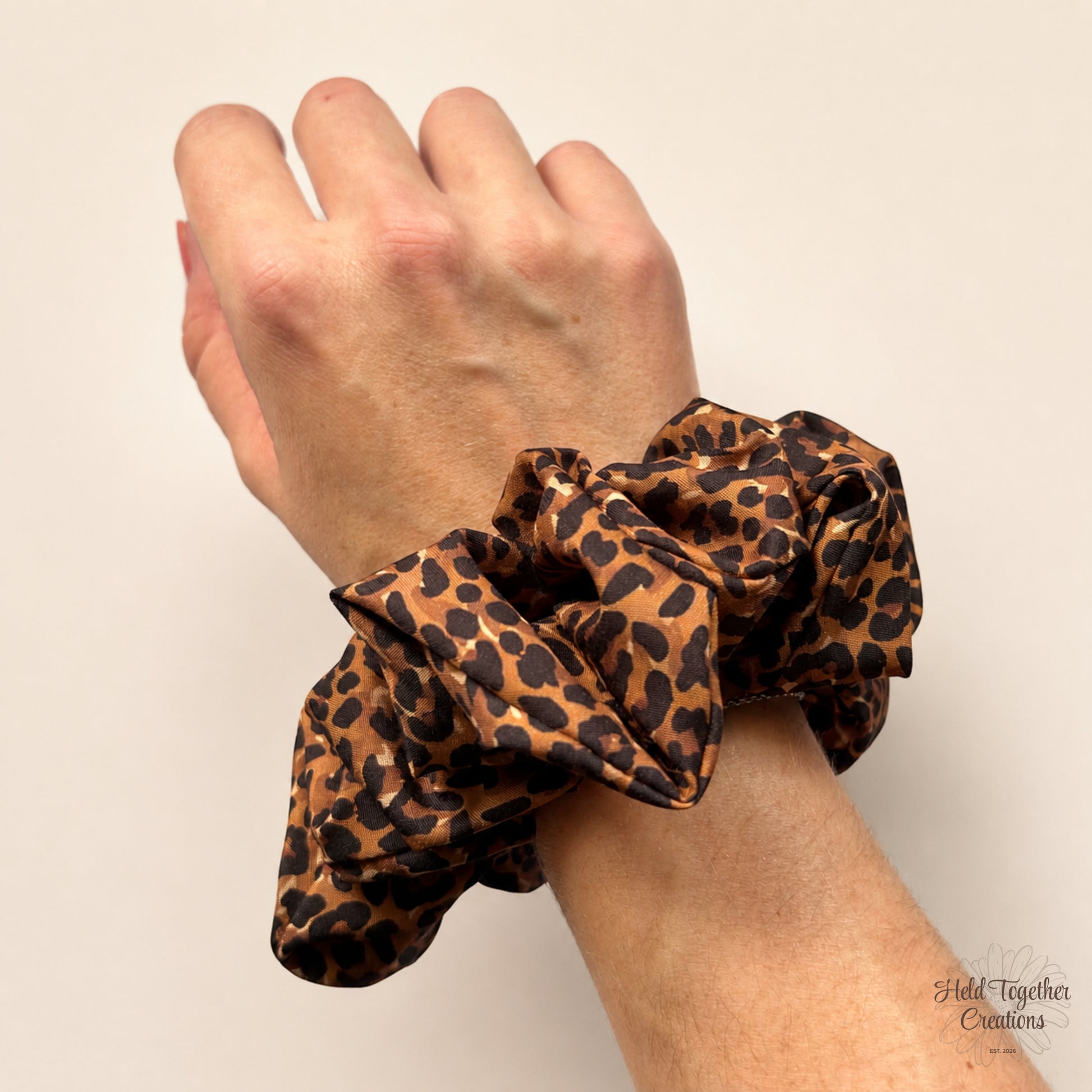 Leopard print XL scrunchie worn on wrist showing soft satin-style fabric and gathered folds.