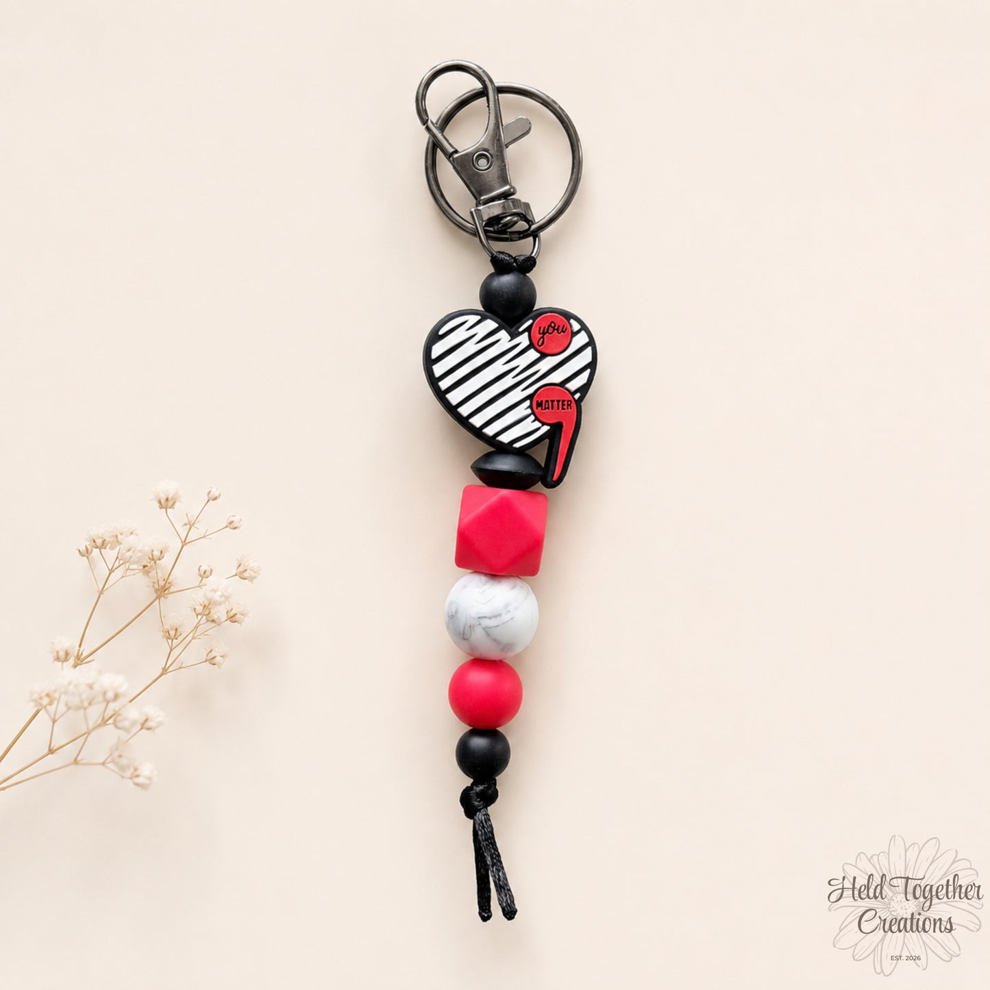 Colorful beaded keychain with heart design on a beige background