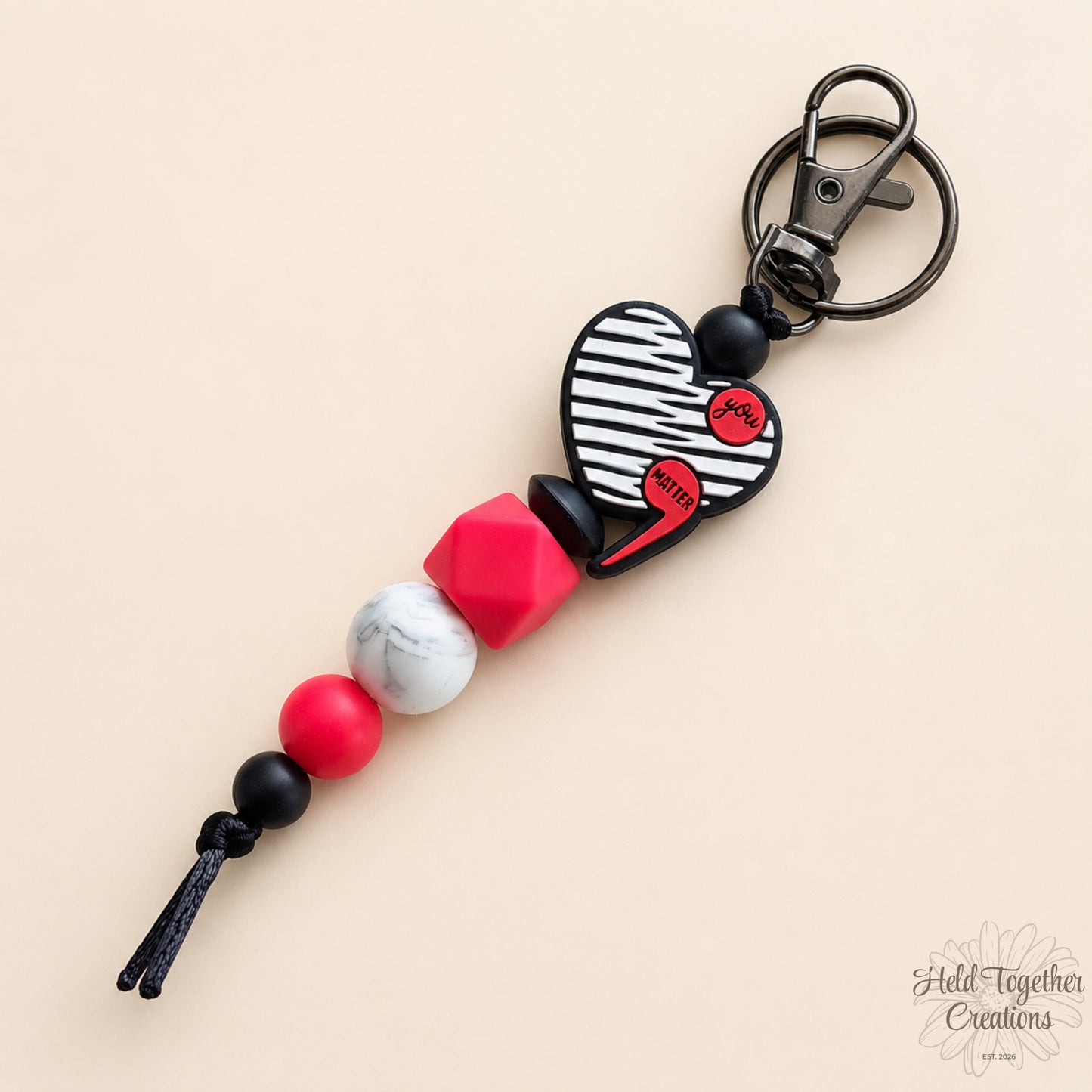 Keychain with heart-shaped design and colorful beads on a beige background